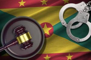 Grenada flag with judge mallet and handcuffs in dark room. Concept of criminal and punishment, background for judgement topics photo