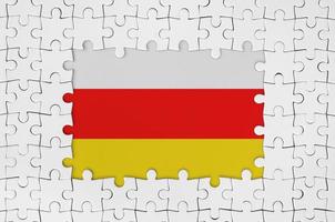 South Ossetia flag in frame of white puzzle pieces with missing central part photo