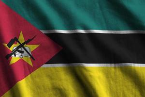 Mozambique flag with big folds waving close up under the studio light indoors. The official symbols and colors in banner photo