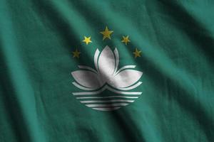 Macau flag with big folds waving close up under the studio light indoors. The official symbols and colors in banner photo