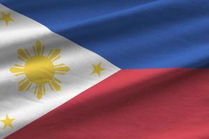 Philippines flag with big folds waving close up under the studio light indoors. The official symbols and colors in banner photo