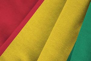 Guinea flag with big folds waving close up under the studio light indoors. The official symbols and colors in banner photo