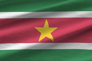 Suriname flag with big folds waving close up under the studio light indoors. The official symbols and colors in banner photo