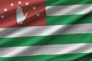 Abkhazia flag with big folds waving close up under the studio light indoors. The official symbols and colors in banner photo