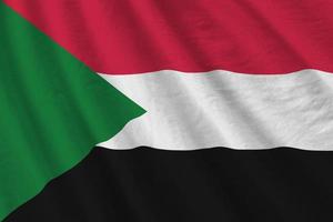 Sudan flag with big folds waving close up under the studio light indoors. The official symbols and colors in banner photo