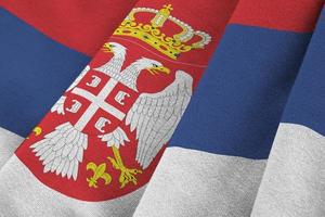 Serbia flag with big folds waving close up under the studio light indoors. The official symbols and colors in banner photo