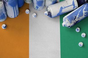 Ivory Coast flag and few used aerosol spray cans for graffiti painting. Street art culture concept photo