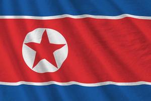 North Korea flag with big folds waving close up under the studio light indoors. The official symbols and colors in banner photo