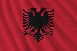 Albania flag with big folds waving close up under the studio light indoors. The official symbols and colors in banner photo