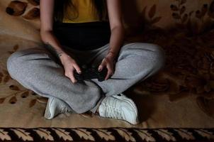 A young girl plays video games with a black joystick with many b photo
