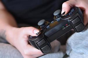 Modern black game controller in the hands of a seated young girl photo