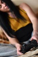 controlador de juego negro moderno en manos de una joven sentada foto