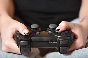 A young girl plays video games with a black joystick with many b photo