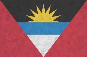 Antigua and Barbuda flag depicted in bright paint colors on old relief plastering wall. Textured banner on rough background photo