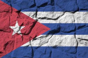 Cuba flag depicted in paint colors on old stone wall closeup. Textured banner on rock wall background photo