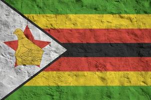 bandera de zimbabwe representada en colores de pintura brillante en la antigua pared de yeso en relieve. banner texturizado sobre fondo áspero foto