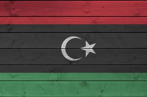 Libya flag depicted in bright paint colors on old wooden wall. Textured banner on rough background photo