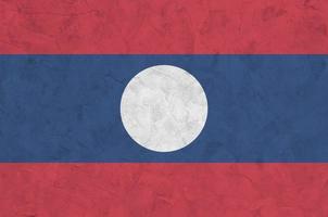 Laos flag depicted in bright paint colors on old relief plastering wall. Textured banner on rough background photo