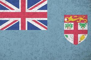 Fiji flag depicted in bright paint colors on old relief plastering wall. Textured banner on rough background photo