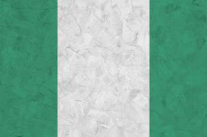 Nigeria flag depicted in bright paint colors on old relief plastering wall. Textured banner on rough background photo