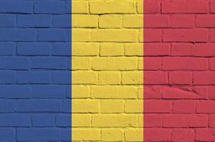 Romania flag depicted in paint colors on old brick wall. Textured banner on big brick wall masonry background photo