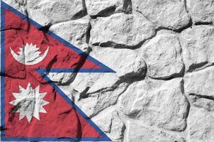 Nepal flag depicted in paint colors on old stone wall closeup. Textured banner on rock wall background photo