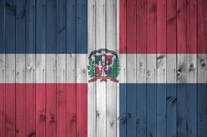 Dominican Republic flag depicted in bright paint colors on old wooden wall. Textured banner on rough background photo