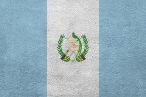 Guatemala flag depicted in bright paint colors on old relief plastering wall. Textured banner on rough background photo