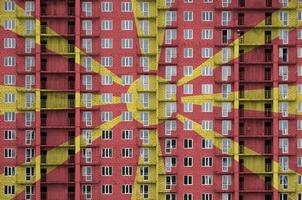 Macedonia flag depicted in paint colors on multi-storey residental building under construction. Textured banner on brick wall background photo