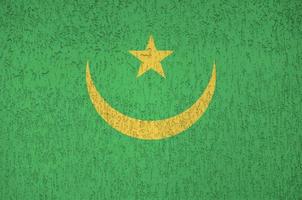 Mauritania flag depicted in bright paint colors on old relief plastering wall. Textured banner on rough background photo