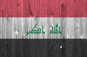 bandera de irak representada en colores de pintura brillante en una pared de madera vieja. banner texturizado sobre fondo áspero foto