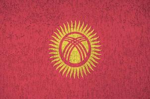 Kyrgyzstan flag depicted in bright paint colors on old relief plastering wall. Textured banner on rough background photo