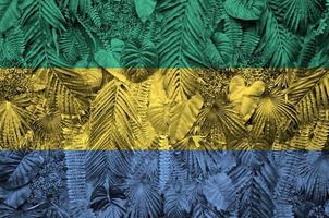 bandera de gabón representada en muchas hojas de palmeras monstera. telón de fondo de moda foto