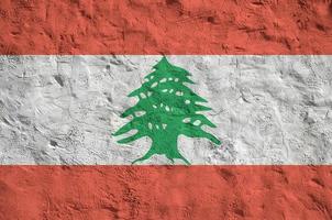 Lebanon flag depicted in bright paint colors on old relief plastering wall. Textured banner on rough background photo