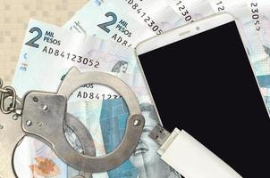 2 Colombian pesos bills and smartphone with police handcuffs. Concept of hackers phishing attacks, illegal scam or malware soft distribution photo