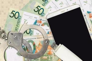50 Belorussian rubles bills and smartphone with police handcuffs. Concept of hackers phishing attacks, illegal scam or malware soft distribution photo