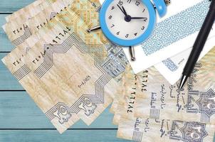 25 Egyptian piastres bills and alarm clock with pen and envelopes. Tax season concept, payment deadline for credit or loan. Financial operations using postal service photo