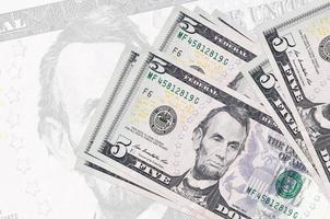 Los billetes de 5 dólares estadounidenses se encuentran apilados en el fondo de un gran billete semitransparente. presentación abstracta de la moneda nacional foto