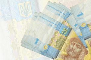 1 billete de hryvnia ucraniano se encuentra apilado en el fondo de un gran billete semitransparente. presentación abstracta de la moneda nacional foto