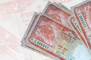 Los billetes de 20 rupias nepalíes se encuentran apilados sobre el fondo de un gran billete semitransparente. presentación abstracta de la moneda nacional foto