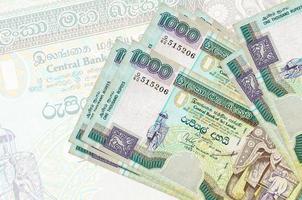 Los billetes de 1000 rupias de Sri Lanka se encuentran apilados en el fondo de un gran billete semitransparente. presentación abstracta de la moneda nacional foto