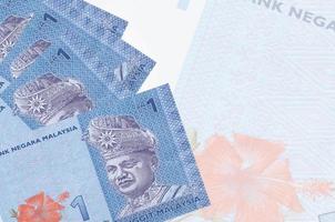 1 Malaysian ringgit bills lies in stack on background of big semi-transparent banknote. Abstract business background photo