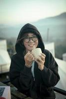 mujer de mediana edad con dientes sonriendo con cara de felicidad sosteniendo una taza de café en la mano foto