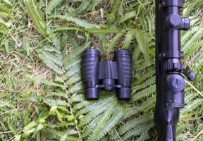 Top view binoculars and rifle on grass floor