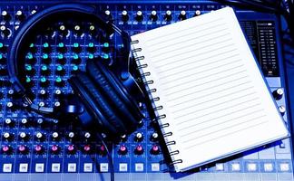 Top view black headphone and notebook on console sound board mixer