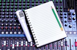 Top view sliver retro vintage microphone and notebook on console sound board mixer photo