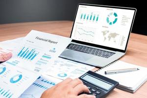 Businessman hand holding financial report document with slide show presentation on display laptop and calculator ,notebook on table in meeting room photo