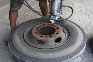 Mechanic is using a tool to remove tires from truck wheels.