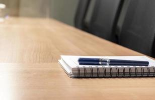 Pen and notebook on table in meeting room photo