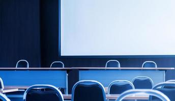 Seminar room with a speaker table in the middle of the stage and whitescreen background photo